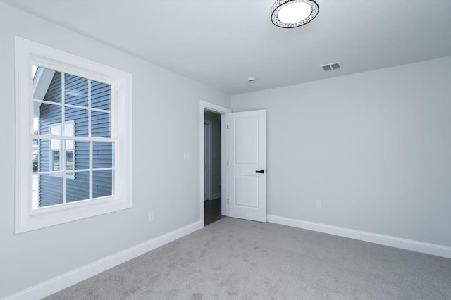 empty room with carpet, baseboards, and visible vents