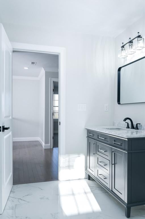 bathroom with marble finish floor, baseboards, ornamental molding, and vanity