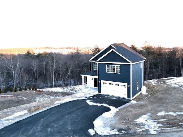 view of home's exterior featuring driveway, a view of trees, and an attached garage