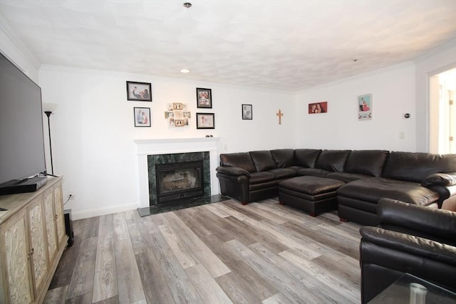 living area with wood finished floors, baseboards, a high end fireplace, and ornamental molding