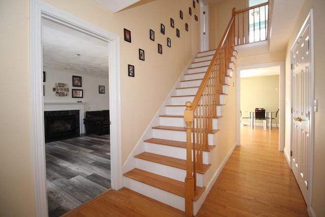 stairway with a fireplace, baseboards, and wood finished floors