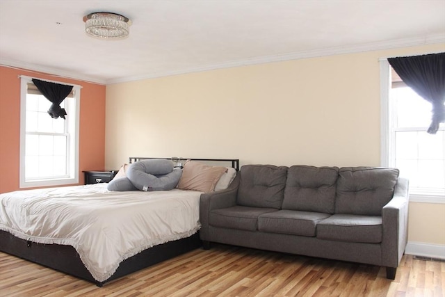 bedroom with multiple windows, baseboards, light wood-style floors, and ornamental molding