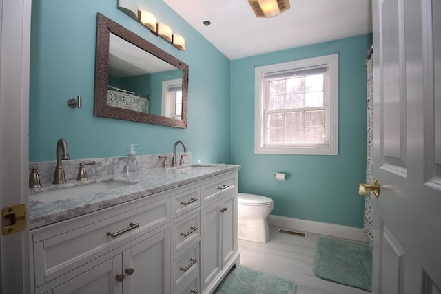 full bath featuring double vanity, toilet, baseboards, and a sink