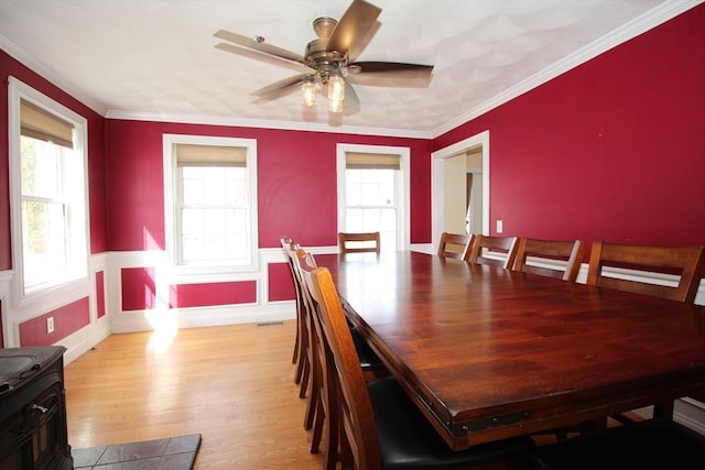 dining area featuring crown molding, a healthy amount of sunlight, and wainscoting