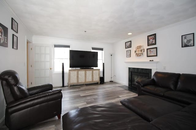 living area featuring crown molding, wood finished floors, a fireplace, and baseboards