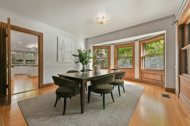 dining space with ornamental molding and light wood-type flooring