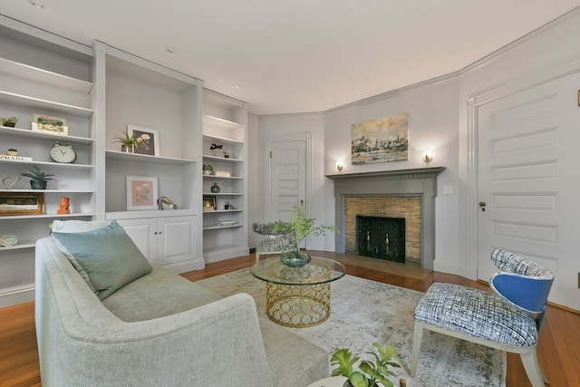 living room featuring ornamental molding, a brick fireplace, hardwood / wood-style flooring, and built in features