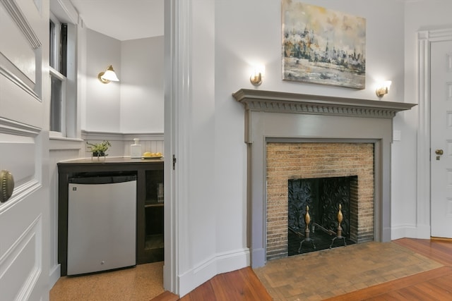 unfurnished living room with wood-type flooring and a brick fireplace