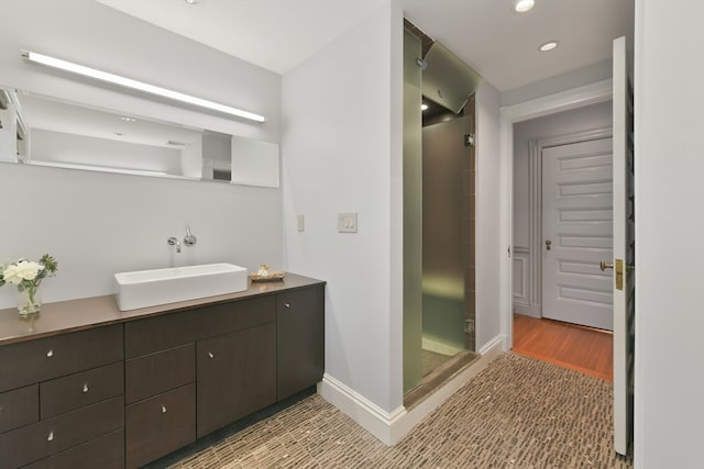 bathroom featuring vanity, wood-type flooring, and a shower with door