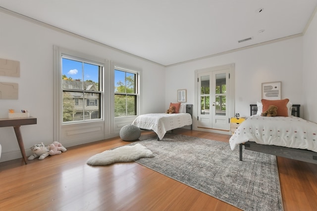 bedroom featuring ornamental molding, access to exterior, wood-type flooring, and french doors