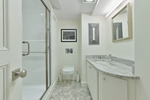 bathroom featuring vanity, a shower with shower door, and toilet