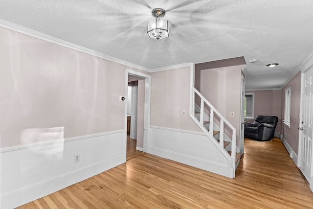 spare room with ornamental molding, a textured ceiling, and hardwood / wood-style flooring