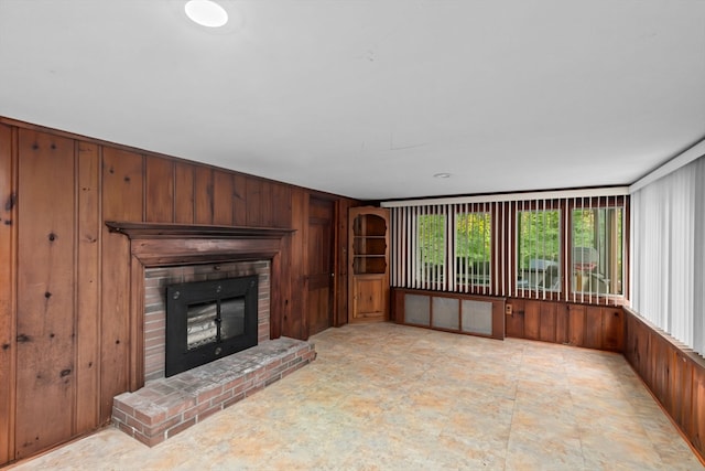 unfurnished living room with a fireplace and wooden walls