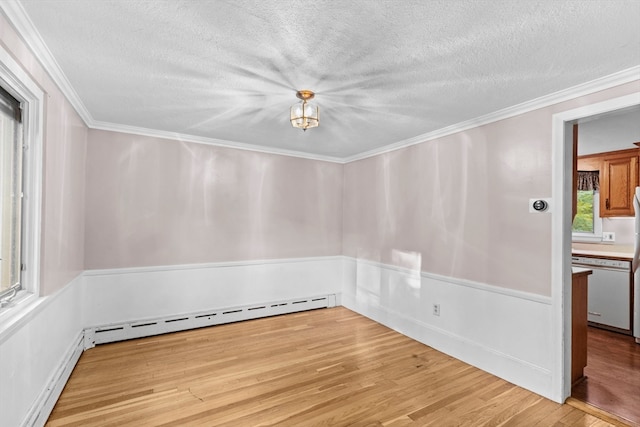 empty room with a baseboard heating unit, light hardwood / wood-style floors, crown molding, and a textured ceiling