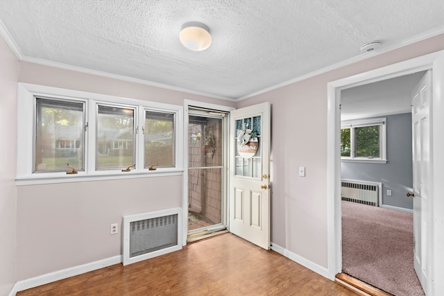 interior space featuring a textured ceiling, ornamental molding, radiator, and hardwood / wood-style floors