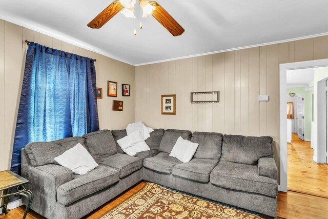 living room with wood-type flooring, ornamental molding, and ceiling fan