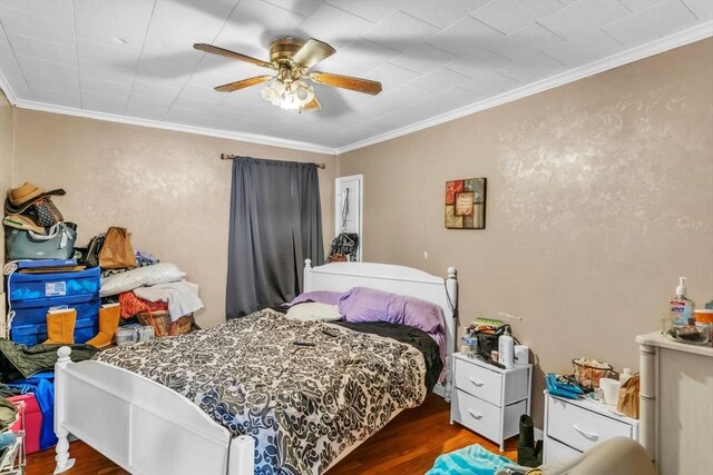 bedroom with crown molding, dark wood-type flooring, and ceiling fan