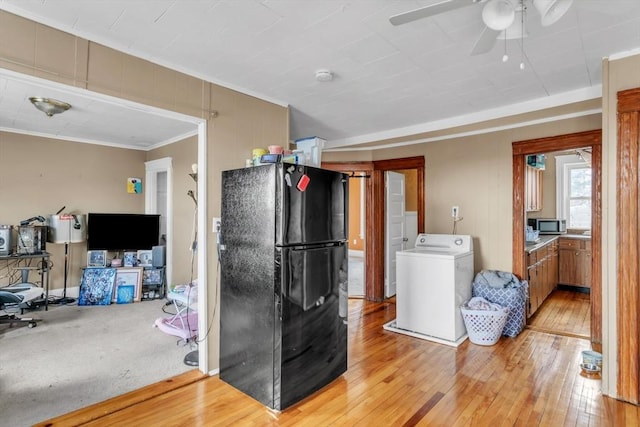 kitchen with ceiling fan, ornamental molding, black fridge, washer / dryer, and light wood-type flooring