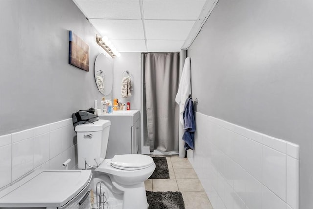 bathroom featuring tile walls, tile patterned flooring, vanity, toilet, and a drop ceiling