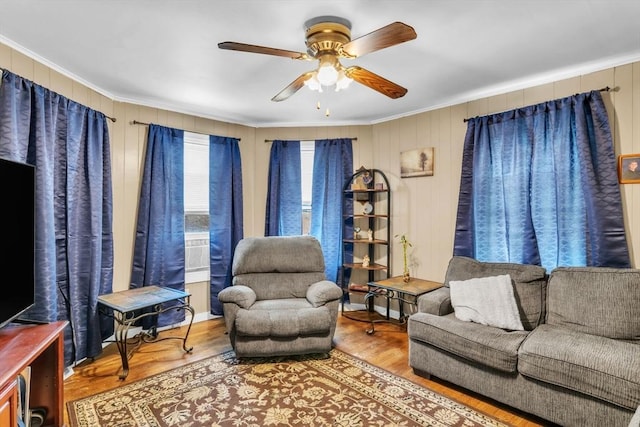 living room with wood-type flooring, ornamental molding, and ceiling fan