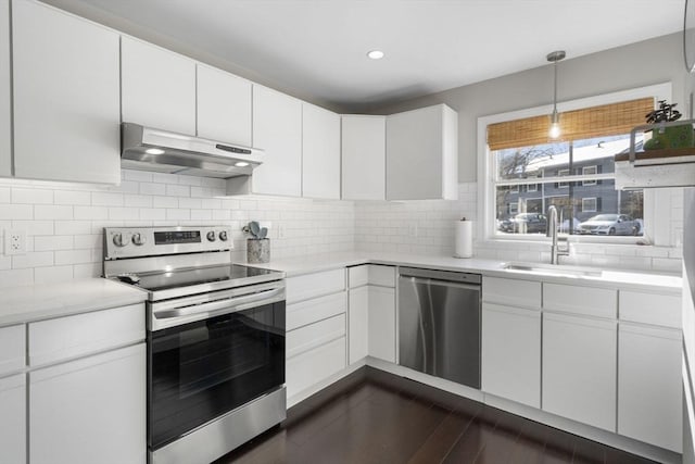 kitchen featuring appliances with stainless steel finishes, light countertops, under cabinet range hood, white cabinetry, and a sink