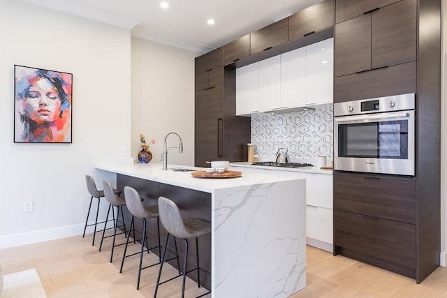 577 Masscahusetts Unit C, Boston, MA 02118 - kitchen with stainless steel oven, a sink, modern cabinets, a kitchen bar, and tasteful backsplash