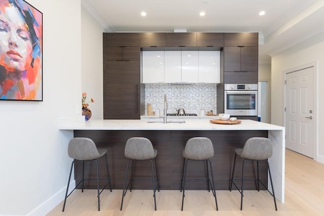 577 Masscahusetts Unit C, Boston, MA 02118 - kitchen with stainless steel oven, a kitchen breakfast bar, modern cabinets, backsplash, and a sink