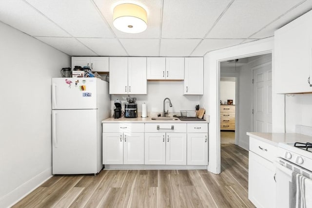 kitchen featuring sink, white appliances, white cabinetry, and a paneled ceiling