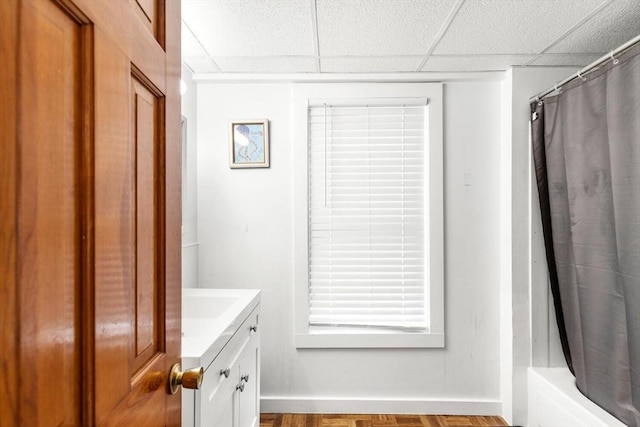 bathroom featuring parquet flooring, a drop ceiling, vanity, and shower / tub combo