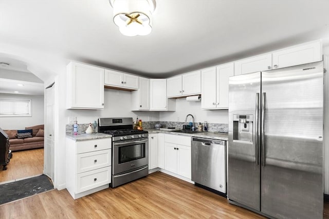 kitchen with sink, stainless steel appliances, white cabinets, and light wood-type flooring