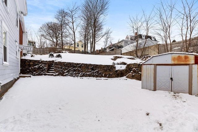 snowy yard featuring a storage shed