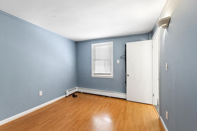 spare room with light hardwood / wood-style floors, crown molding, and baseboard heating