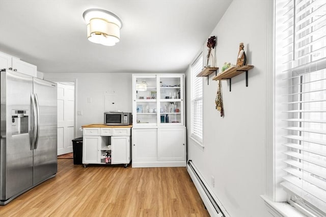 kitchen with light hardwood / wood-style floors, appliances with stainless steel finishes, wooden counters, a baseboard heating unit, and white cabinets