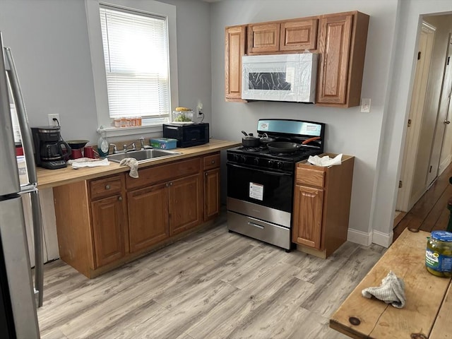 102-104 Robey St, Boston, MA 02119 - kitchen featuring gas stove, light countertops, a sink, white microwave, and light wood finished floors