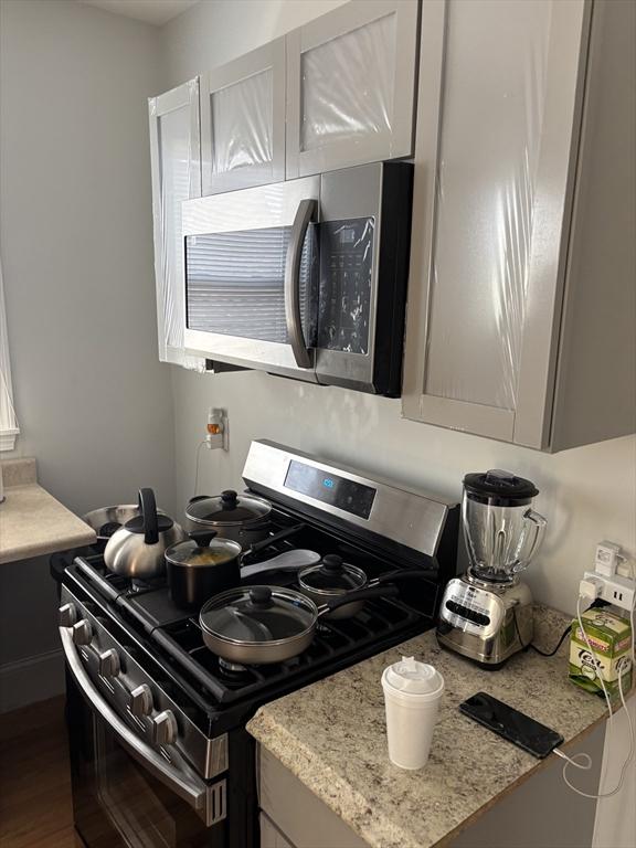 102-104 Robey St, Boston, MA 02119 - kitchen with appliances with stainless steel finishes and dark wood-style floors