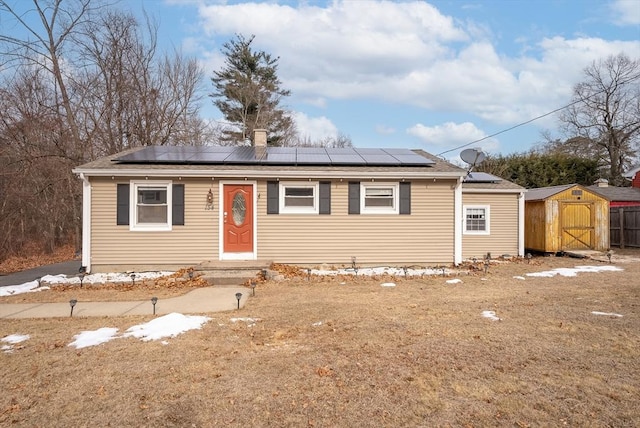 single story home featuring solar panels and a storage unit