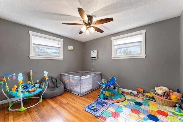 playroom with ceiling fan, hardwood / wood-style floors, and a textured ceiling