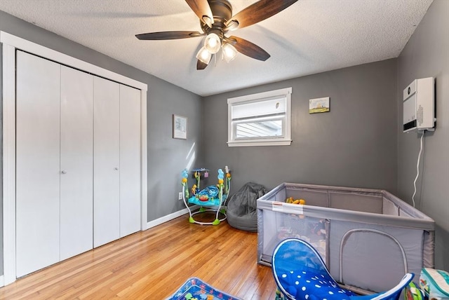 bedroom with ceiling fan, a textured ceiling, a closet, and light wood-type flooring