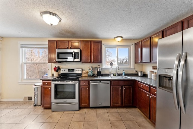 kitchen featuring a wealth of natural light, appliances with stainless steel finishes, sink, and light tile patterned floors