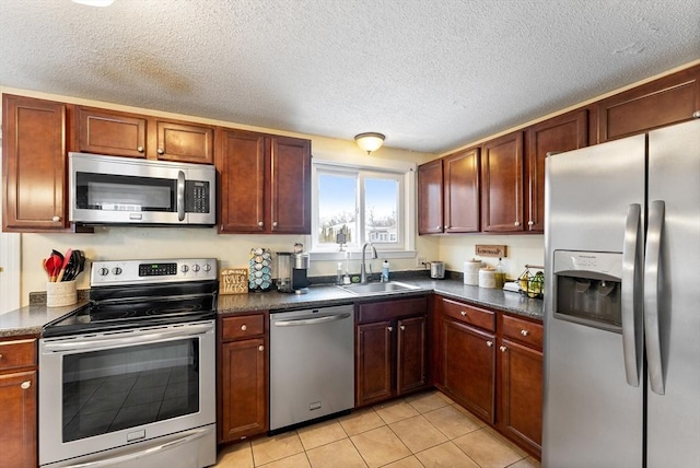 kitchen with light tile patterned flooring, appliances with stainless steel finishes, sink, and a textured ceiling