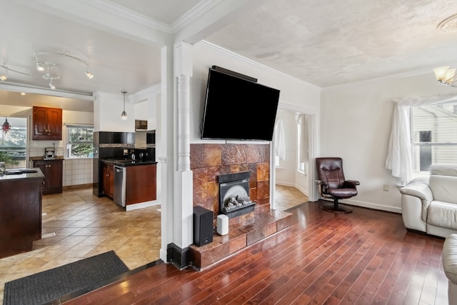 living room with light wood-type flooring, a tile fireplace, and ornamental molding