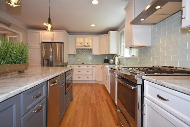 24 Sheppard Rd, Bourne, MA 02562 - kitchen featuring appliances with stainless steel finishes, exhaust hood, white cabinetry, ornamental molding, and light wood-style floors