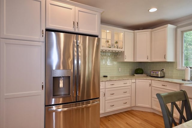 24 Sheppard Rd, Bourne, MA 02562 - kitchen with stainless steel fridge with ice dispenser, white cabinetry, light wood finished floors, backsplash, and light stone countertops