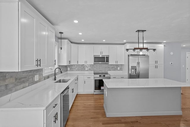 kitchen with sink, a center island, hanging light fixtures, and appliances with stainless steel finishes