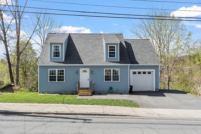 cape cod home with a front yard, an attached garage, a shingled roof, and driveway