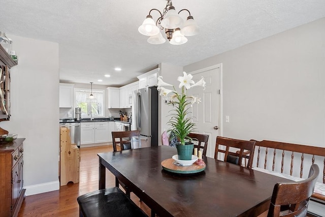 dining space with recessed lighting, light wood-type flooring, baseboards, and a notable chandelier