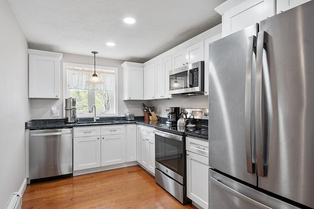kitchen featuring white cabinetry, appliances with stainless steel finishes, a baseboard radiator, and a sink