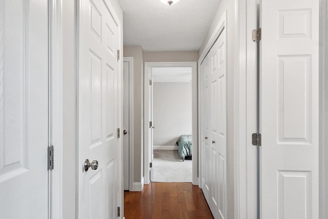 corridor with baseboards, dark wood finished floors, and a textured ceiling