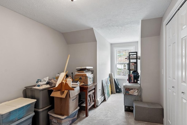 interior space featuring a textured ceiling, a baseboard heating unit, and carpet floors