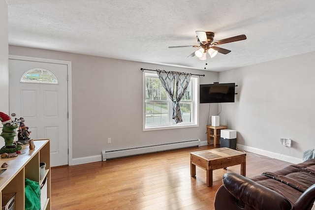 living room featuring a textured ceiling, light wood finished floors, a ceiling fan, baseboard heating, and baseboards